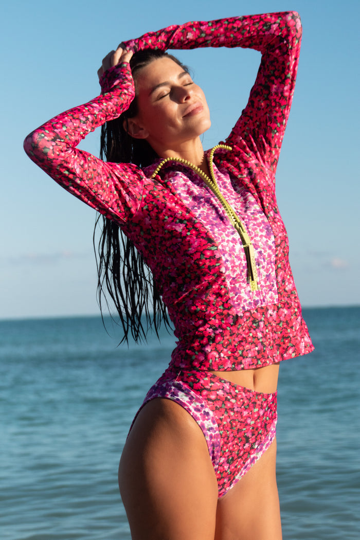 Female model in front of blue sky and ocean background wearing Mia tee and Belle bikini bottom in Mini Floral