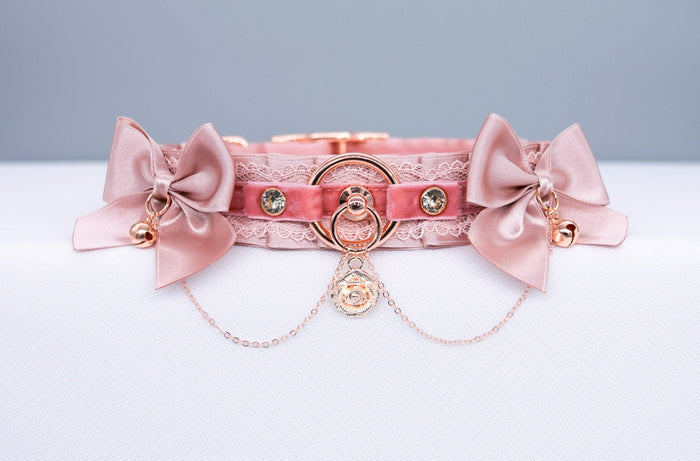 A luxury BDSM collar in rose gold color, featuring dusty rose satin and blush satin bows, rose gold hardware, and a rose gold chain with a rose charm.