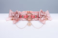 A luxury BDSM collar in rose gold color, featuring dusty rose satin and blush satin bows, rose gold hardware, and a rose gold chain with a rose charm.