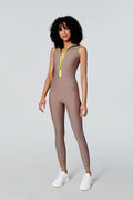 Female model wearing Watskin Chloe sleeveless catsuit in Taupe featuring a neon front zipper