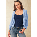 Woman wearing a blue cardigan over a navy top and jeans against a beige background