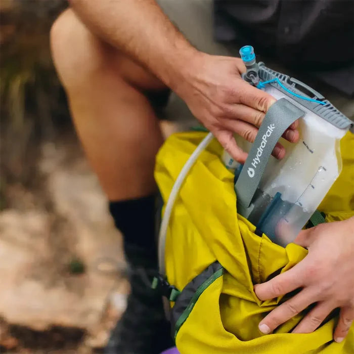Close-up of HydraPak Contour Clear Water Reservoir being packed into a yellow hiking bag, emphasizing ease of use and outdoor readiness.  from  John Bull Clothing