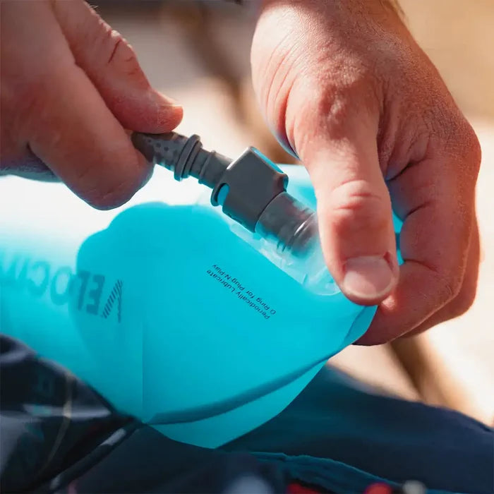 Close-up of hands connecting the hose to the HydraPak Velocity Hydration Water Reservoir, highlighting its secure and leak-proof valve system.  from  John Bull Clothing