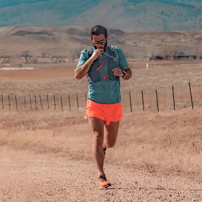 Trail runner drinking from the HydraPak Velocity Hydration Water Reservoir while running, showing its convenience for endurance sports.  from  John Bull Clothing