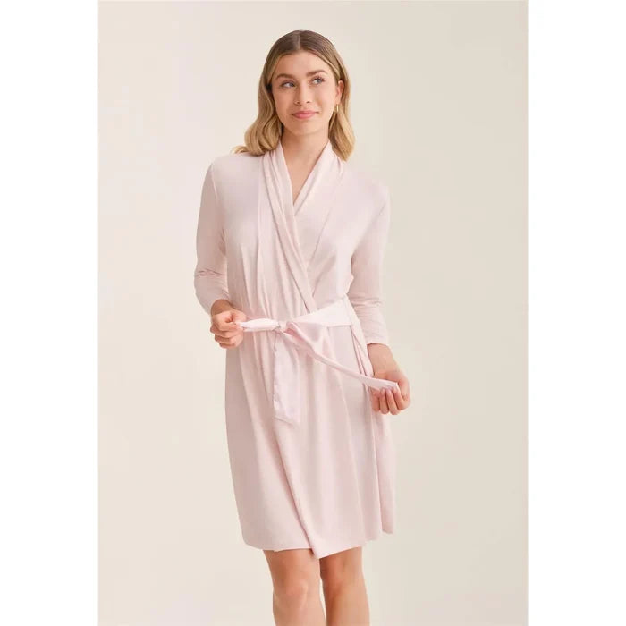 Woman wearing a light pink robe against a plain background