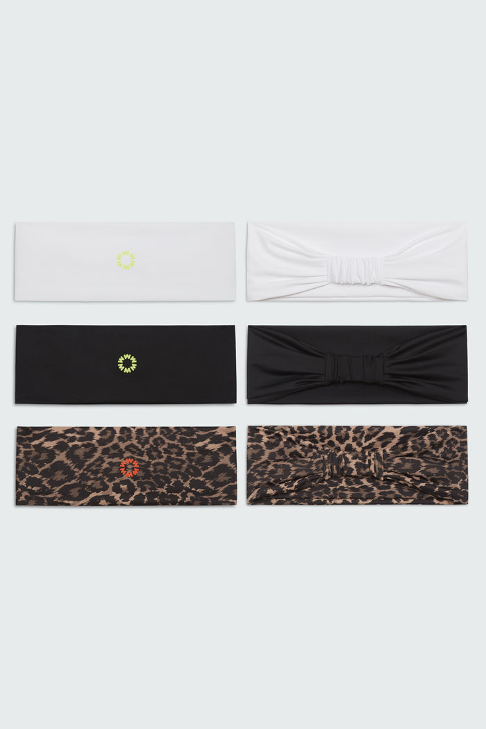 Close up photo of six Watskin Lilly headbands in Multi, each featuring a different look. Top two are white, middle two are black and bottom two are brown leopard print. One each of the black and white features a bow detail.