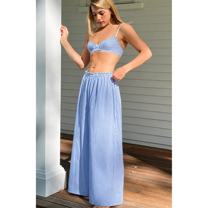 Woman wearing a blue striped outfit on a wooden deck.