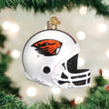 A white football helmet Christmas ornament with the Oregon State Beavers logo hangs from a green Christmas tree, surrounded by glowing lights.