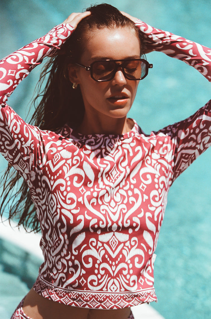 Woman in sunglasses standing poolside modeling Watskin Sasha tee in Dusty Rose Ikat