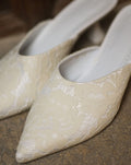A close-up of the Satin Slippers, showcasing the pointed-toe silhouette and luminous satin finish.